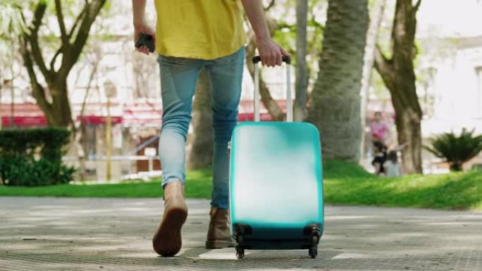 旅行的年轻人带着手提箱穿过公园