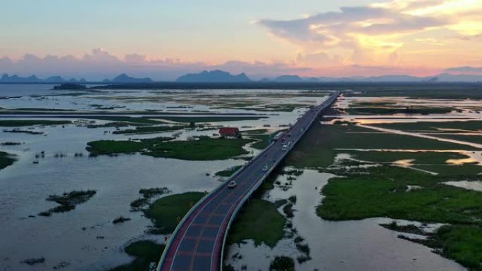 日落时沿着乡村道路行驶的汽车鸟瞰图