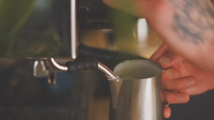 咖啡师由浓缩咖啡机蒸牛奶
