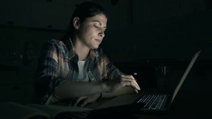女人在深夜使用笔记本电脑。