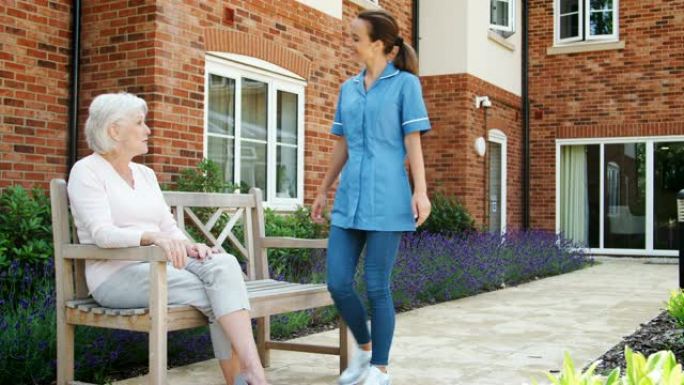 资深女性坐在长凳上，与养老院的护士交谈