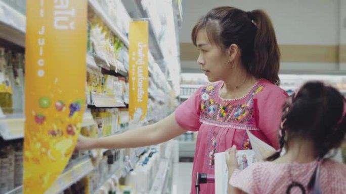 年轻女子和她的女婴在商店里选择乳制品