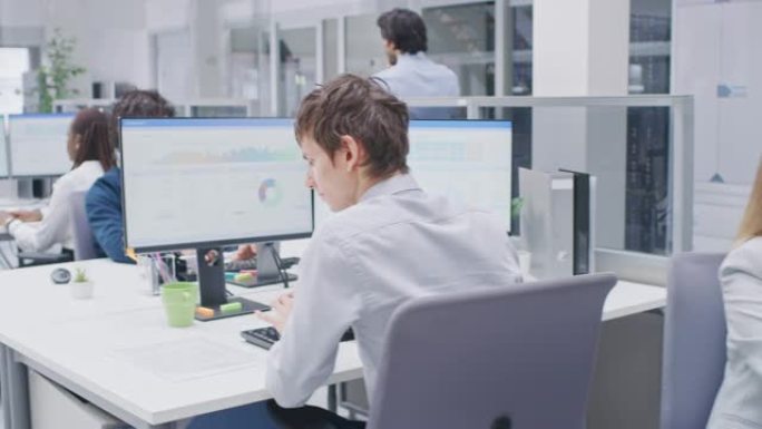 在明亮的大办公室里，年轻的专业人士在台式计算机上工作，交谈，做客户支持，与客户沟通，监控统计数据。漫