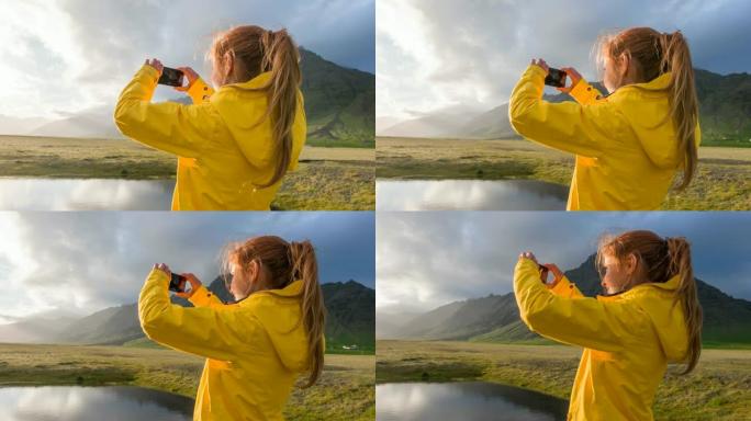 女性游客欣赏冰岛的风景，用智能手机拍照