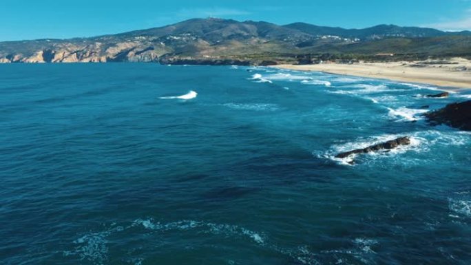 空中无人机镜头: 葡萄牙岩石海岸，海景优美。飞越葡萄牙，海岸线上碧绿的海浪在沙滩上滚动。Praia 
