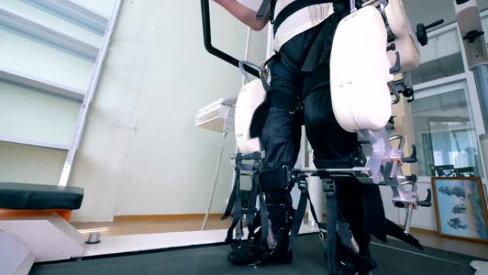 患有身体障碍的男性患者正在步行轨道模拟器上锻炼。康复用电子医疗机器人。