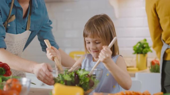 在厨房: 母亲和小女儿一起烹饪健康晚餐。妈妈教小女孩健康的习惯，以及如何在沙拉碗中混合蔬菜。可爱的孩