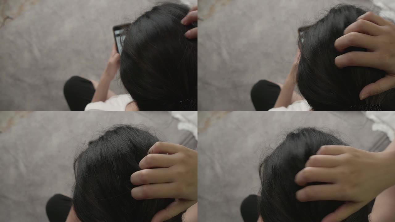 亚洲妇女使用智能手机并挠头。皮肤病，