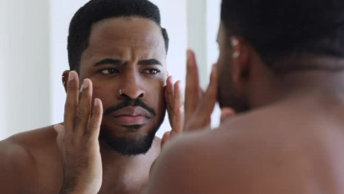 年轻的非洲男子照镜子有面部皮肤问题