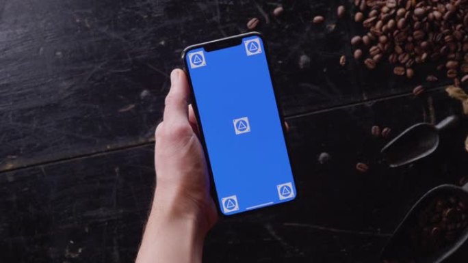 带咖啡豆的木制桌子上的蓝屏智能手机