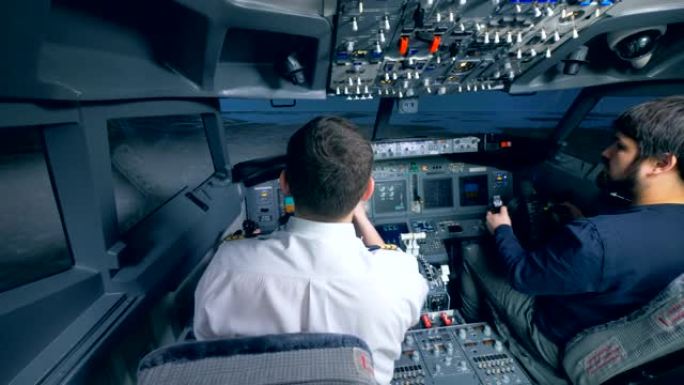 飞行教练正在向另一个人演示如何管理飞行模拟器
