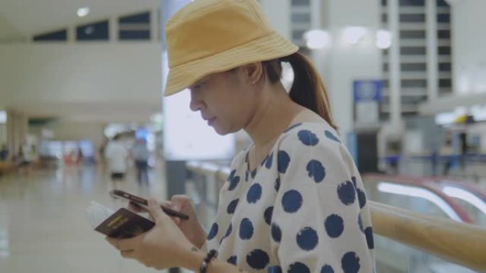 亚洲旅游妇女在机场候机楼等候和使用智能手机。