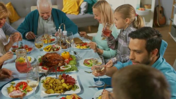 大家庭和朋友在家里庆祝，各种各样的年轻人和老人聚集在餐桌旁。吃饭、分享食物、喝酒和愉快的交谈。白天的