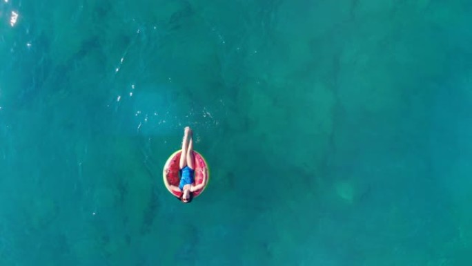 年轻女子躺在橡皮圈上，漂浮在海里。