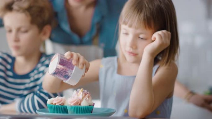 在厨房里: 可爱的小女儿的肖像在奶油蛋糕糖霜上撒上Funfetti。家庭一起煮松饼。可爱的孩子帮助他