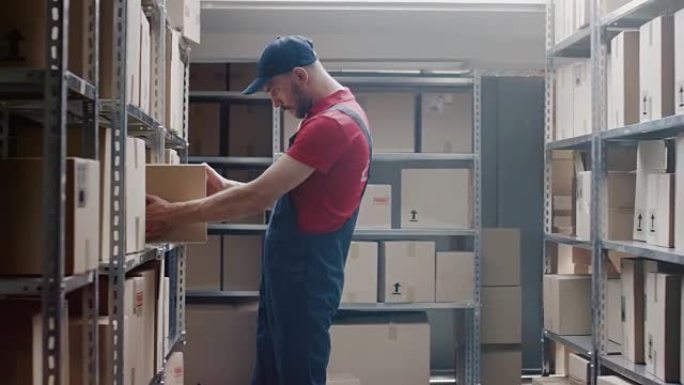 英俊的仓库工人带着一个纸板箱走进储藏室，把它放在架子上。