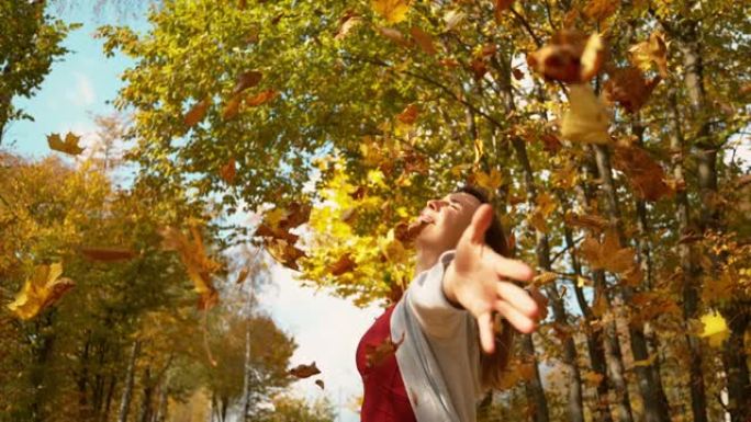 复制空间: 无忧无虑的女人让五颜六色的叶子落在她身上的电影镜头