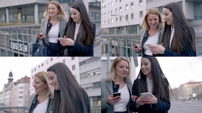 女士快乐的年轻女商人朋友在城市散步和使用智能手机