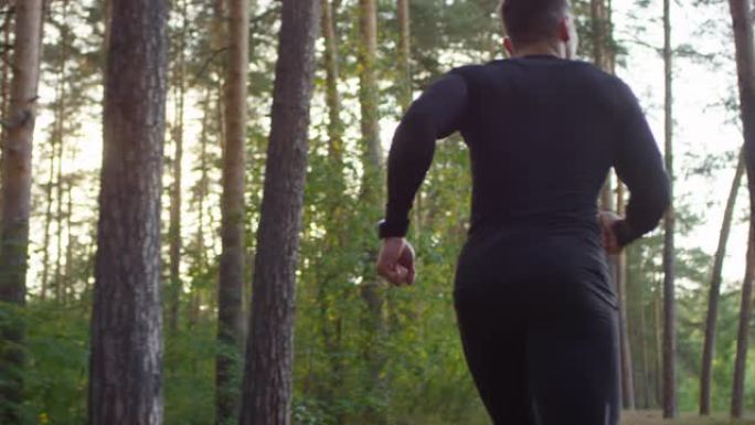 早上在森林小径上奔跑的肌肉男人的后景