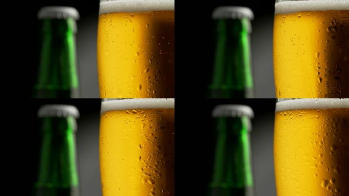 旋转金色泡沫啤酒杯覆盖水滴。背景中的绿色啤酒瓶。特写镜头，4K