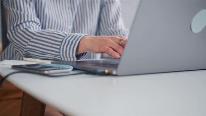年轻美丽的女商人的特写手在轻便的现代简约办公桌上与笔记本电脑触摸条一起工作。