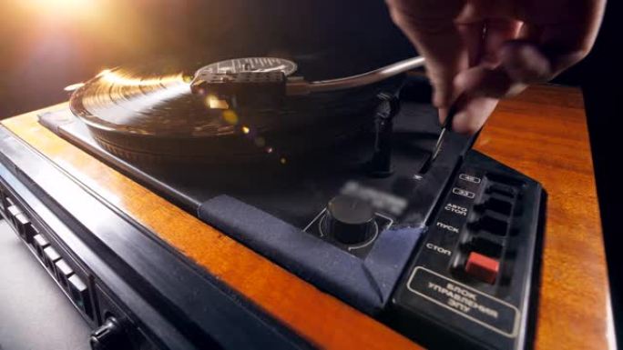 一个人将黑胶唱片放到音乐播放器上并启动它。