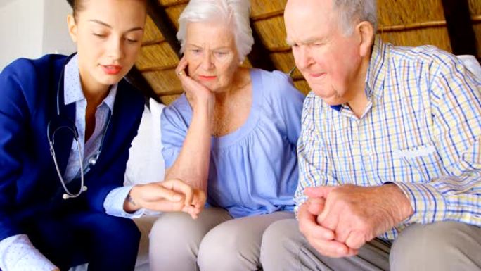 高加索女医生在舒适的家中与老年夫妇讨论药物治疗的前视图4