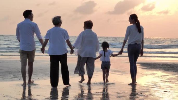 剪影快乐的亚洲大家庭步行到沙滩上日落冲浪。家庭，生活方式，人，人寿保险，多代，老人，假期，关系，孩子