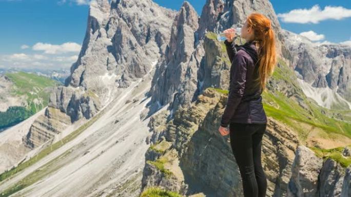 Seceda山上的女人探索意大利多洛米蒂，用可重复使用的水瓶补水