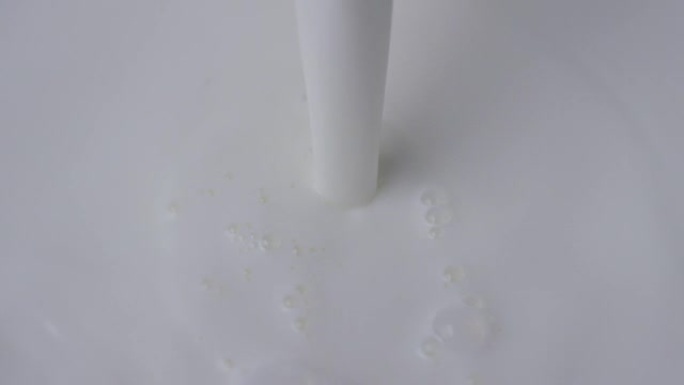 一只手在一个特殊的透明杯中慢动作倒入牛奶和早餐。