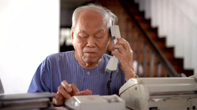 资深亚洲男子在家使用复古电话