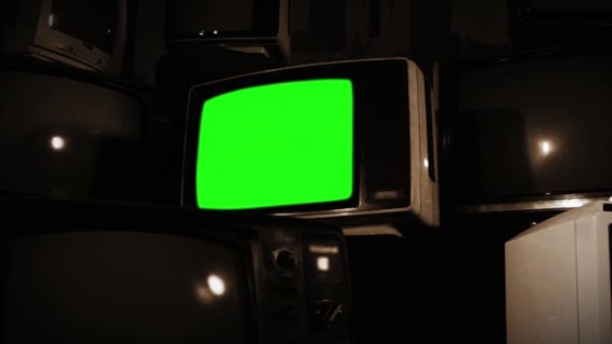 一堆旧电视上有绿屏的旧电视。棕褐色色调。快速缩小。
