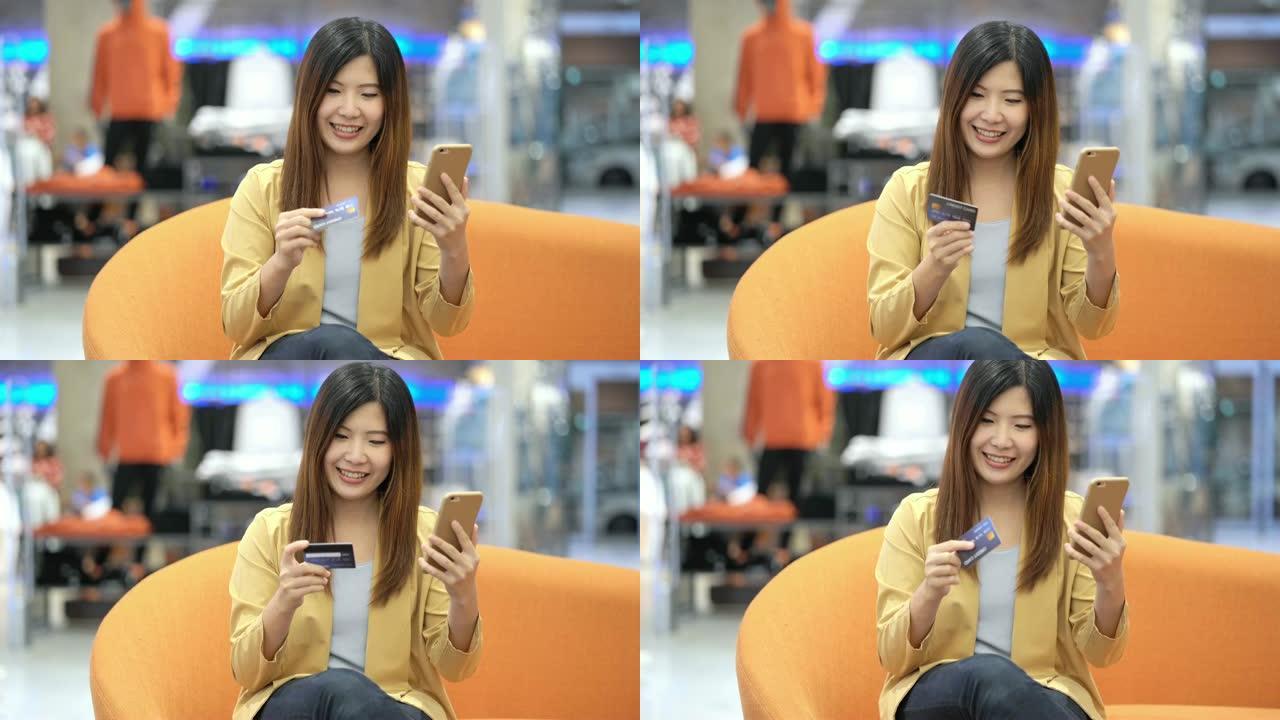 4k镜头亚洲女性使用信用卡和手机在线购物的场景百货商店无现金，科技钱包和在线支付概念，信用卡模型