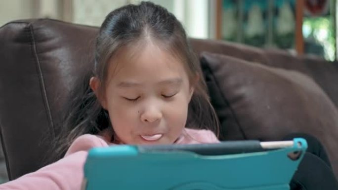 一个女孩边看平板电脑边吹泡泡糖