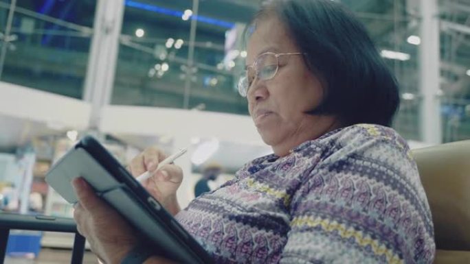 亚洲资深女性在机场使用平板电脑