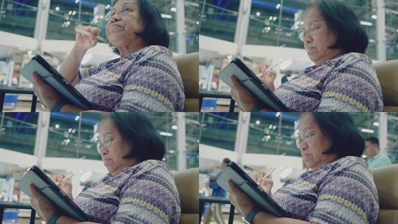 亚洲资深女性在机场使用平板电脑