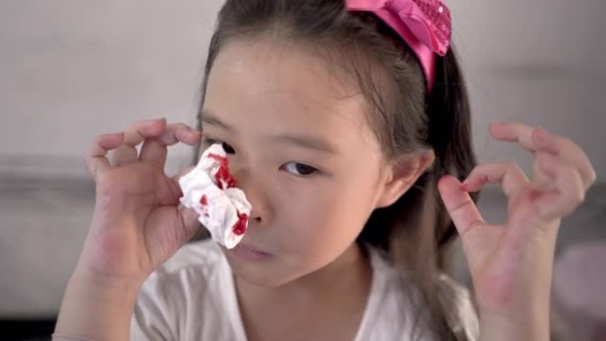一个小女孩用薄纸擦拭流血的鼻子的特写