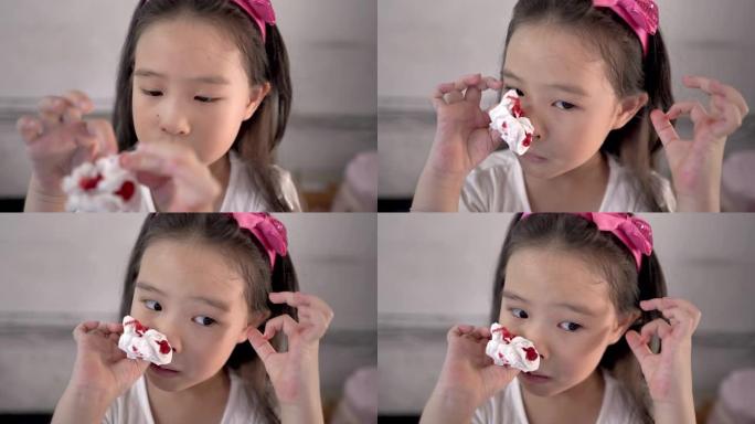 一个小女孩用薄纸擦拭流血的鼻子的特写