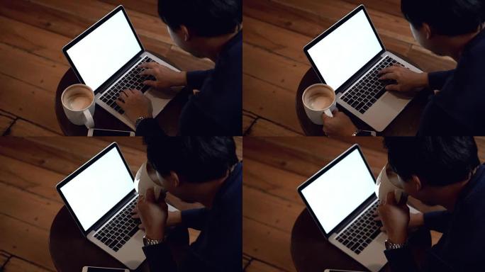 4k镜头亚洲商人与休闲服装喝咖啡和与咖啡咖啡馆的白屏笔记本电脑工作的场景，生活方式和休闲概念
