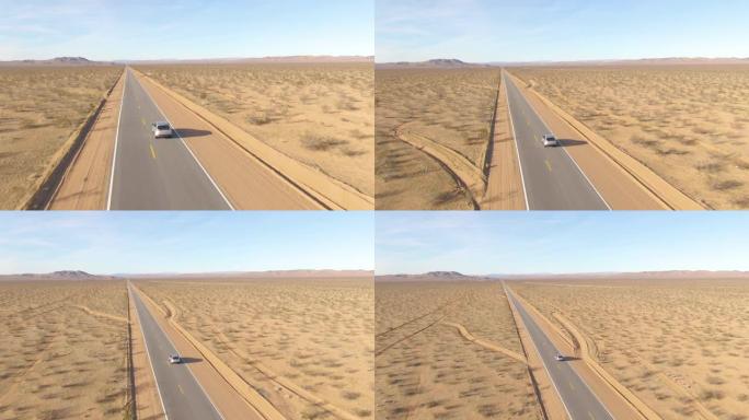 无人机: 贫瘠的风景环绕着一辆银色SUV在空旷的高速公路上行驶。
