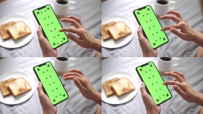 特写女人手使用智能手机绿屏早餐，垂直
