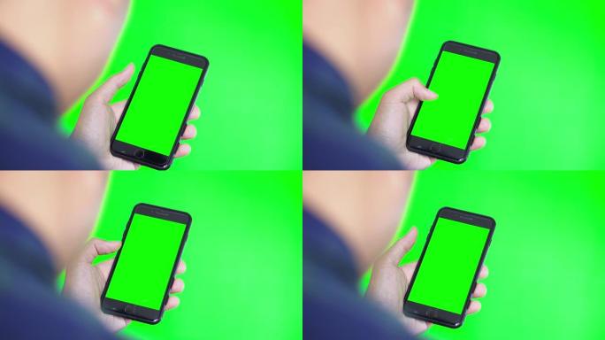 绿色屏幕和绿色背景的智能手机的肩膀拍摄