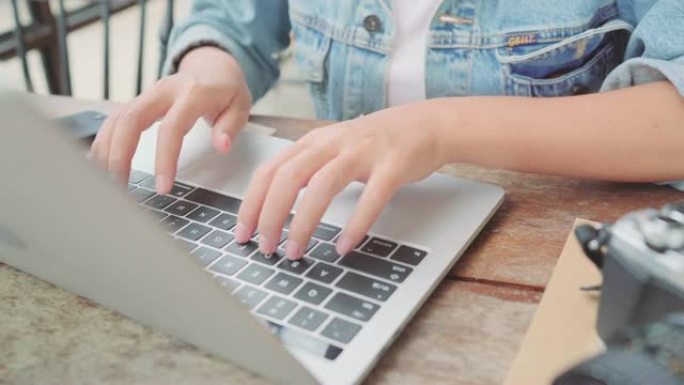 商业自由亚洲女性工作，在笔记本电脑上做项目，在咖啡馆坐在桌子上使用智能手机。生活方式聪明的美女在咖啡