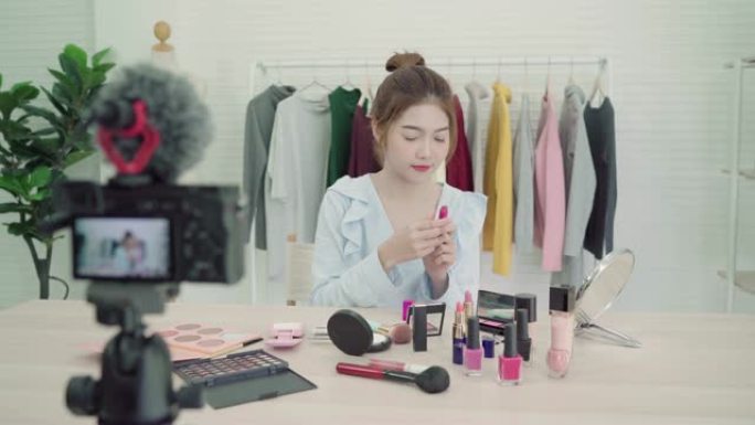 美容博主呈现美容化妆品坐在前置摄像头录制视频。美丽的亚洲女人使用化妆品，同时复习化妆教程通过互联网向