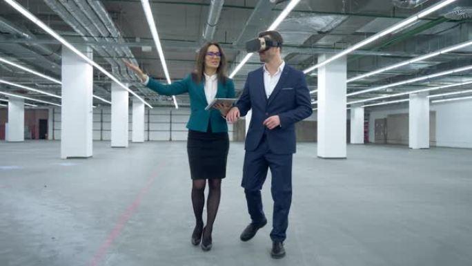 商业地产概念。戴着VR眼镜的商人正在大厅里与一位女经理一起散步