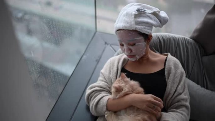 一名亚洲华裔少女在卧室里用猫做面部水疗面膜