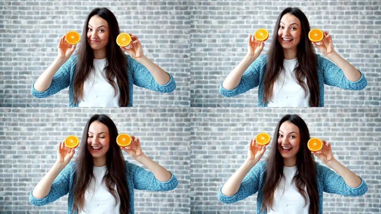 漂亮的女士拿着橘子在砖墙背景上微笑的肖像