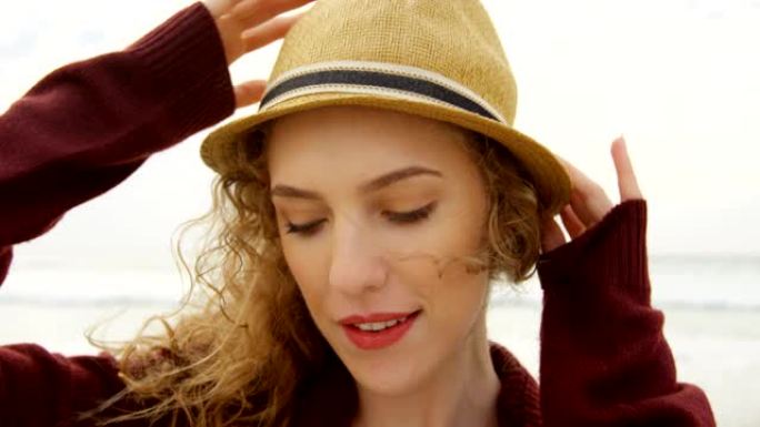 海滩上戴着帽子的年轻美丽高加索女人的前视图4k