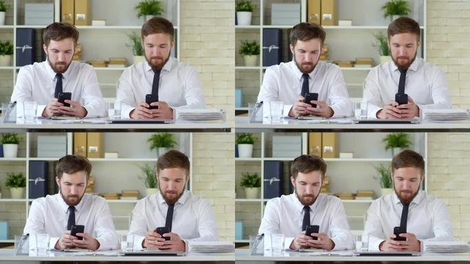 男性双胞胎在工作中使用智能手机