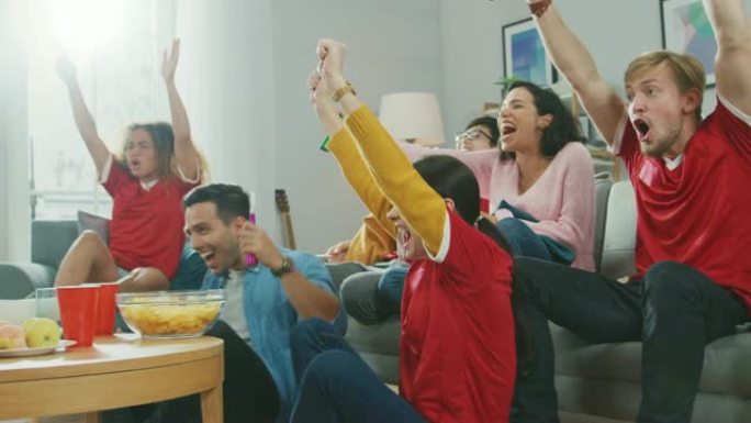 在家里，一群穿着球队制服的体育迷在电视上观看体育比赛，他们为球队加油，在球队进球后庆祝胜利。舒适的房